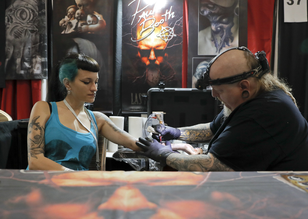 In this picture taken on Sunday, Oct. 16, 2016, Paul Booth of the U.S., one of the world's most famous tattoo artists, works during the International Tattoo Convention Bucharest 2016 in Bucharest, Romania. More than 100 tattoo and piercing artists brought their skills and art to a three-day convention in the Romanian capital.(AP Photo/Vadim Ghirda)